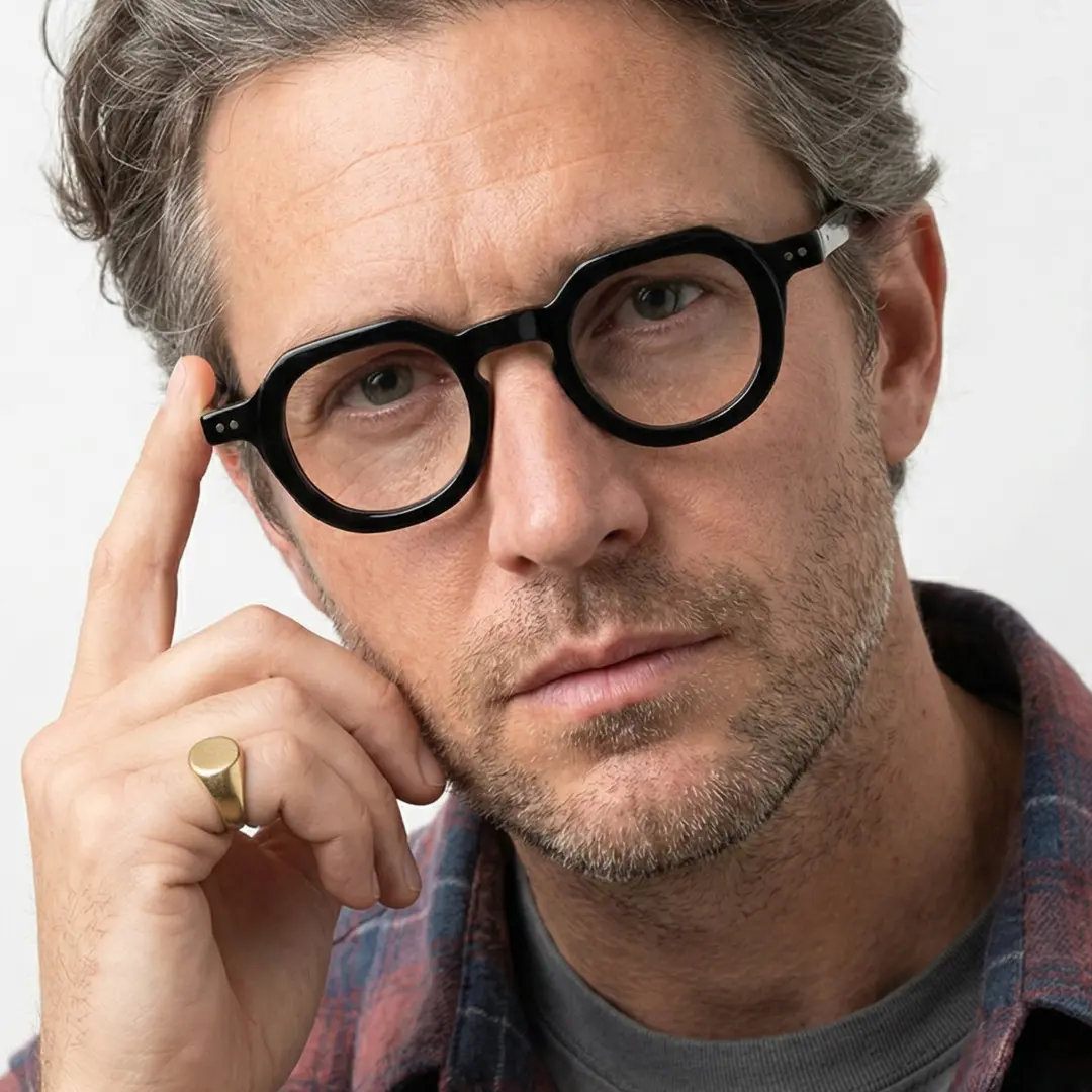 Three-quarter view of male wearing vintage black geometric eyeglasses, hand resting on forehead, thoughtful expression, GA0032301
