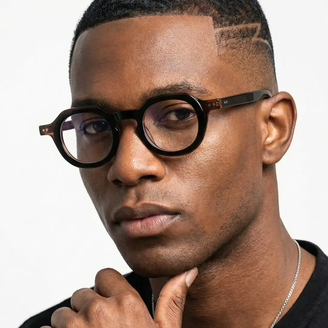 Face close-up view of male wearing brown geometric eyeglasses, resting chin on hand, neutral expression, GA0032301