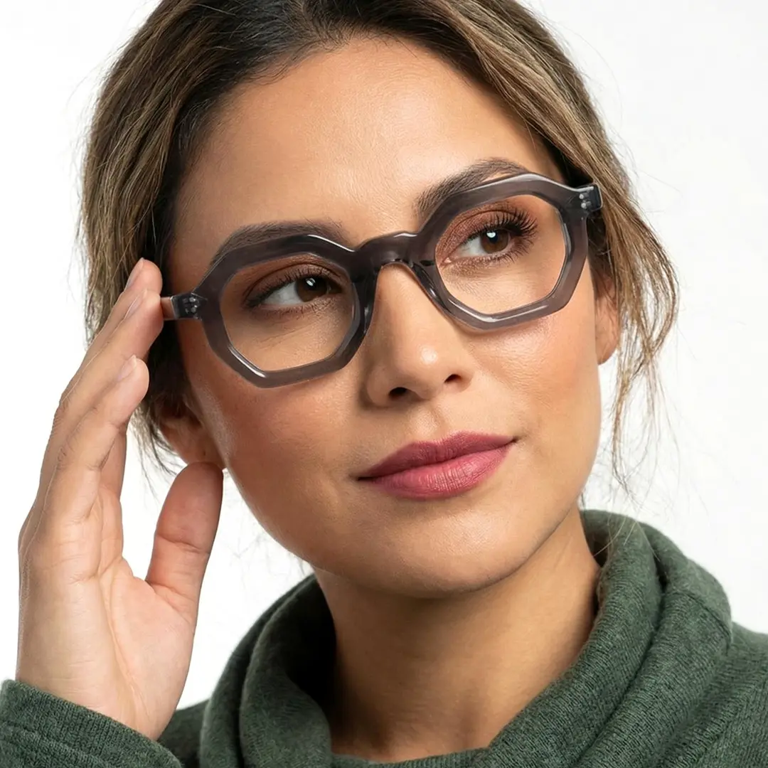 Front view of female wearing grey geometric eyeglasses, touching frame, soft smile, GA0052310