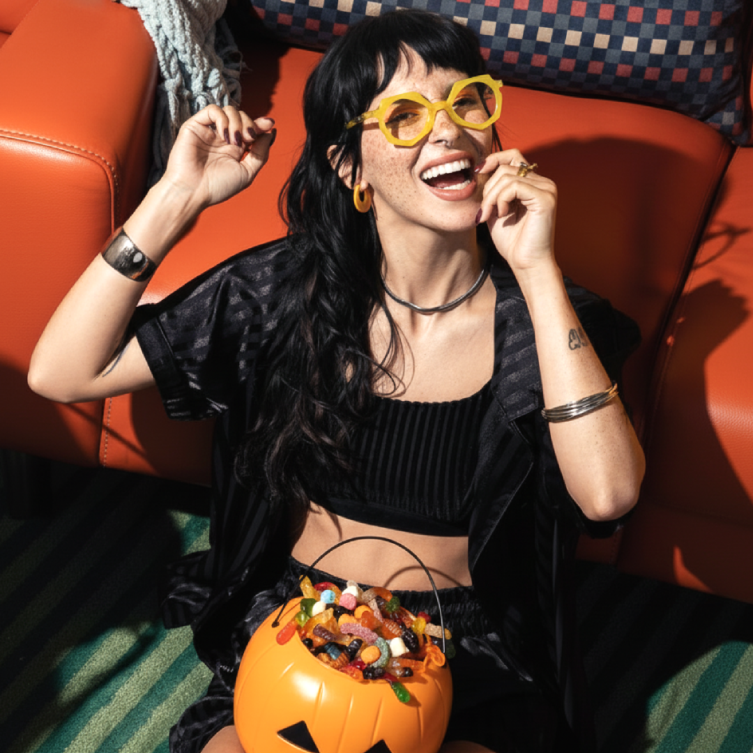 Profile view of female wearing yellow geometric eyeglasses, resting chin on hand, smiling, GA0062309