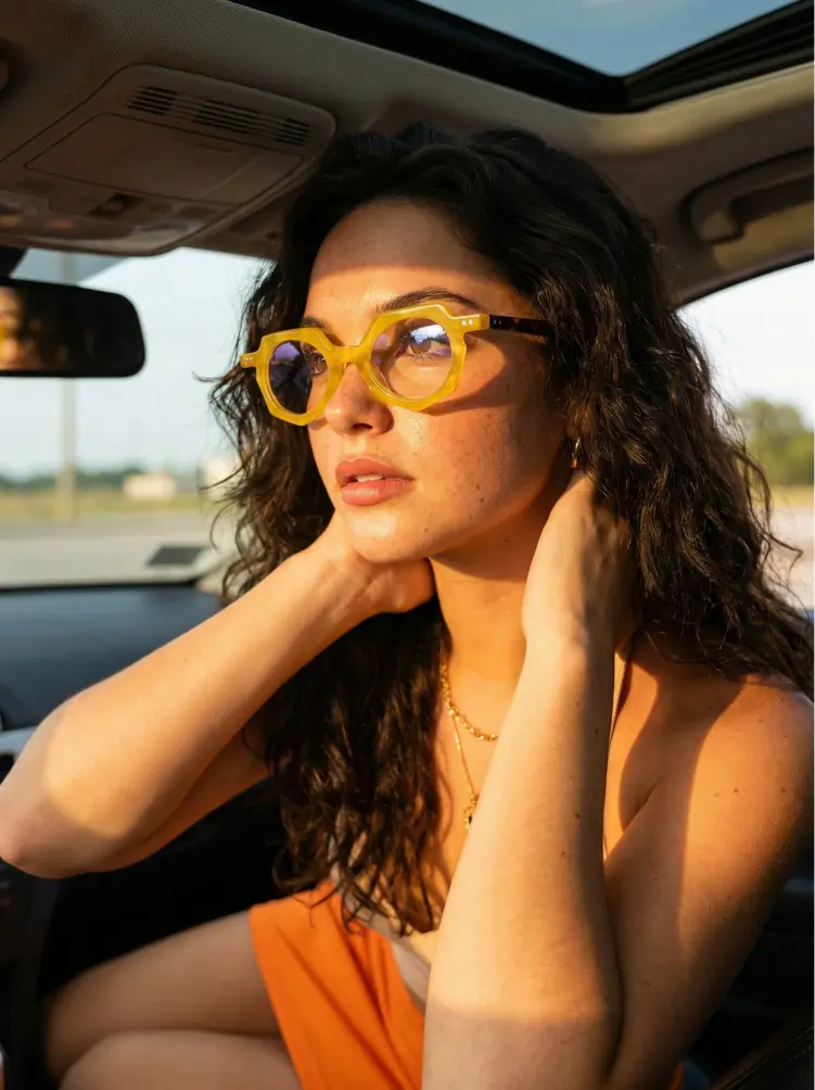 Female model wearing vintage yellow geometric acetate eyeglasses in a car during golden hour. SPU: GA0062309