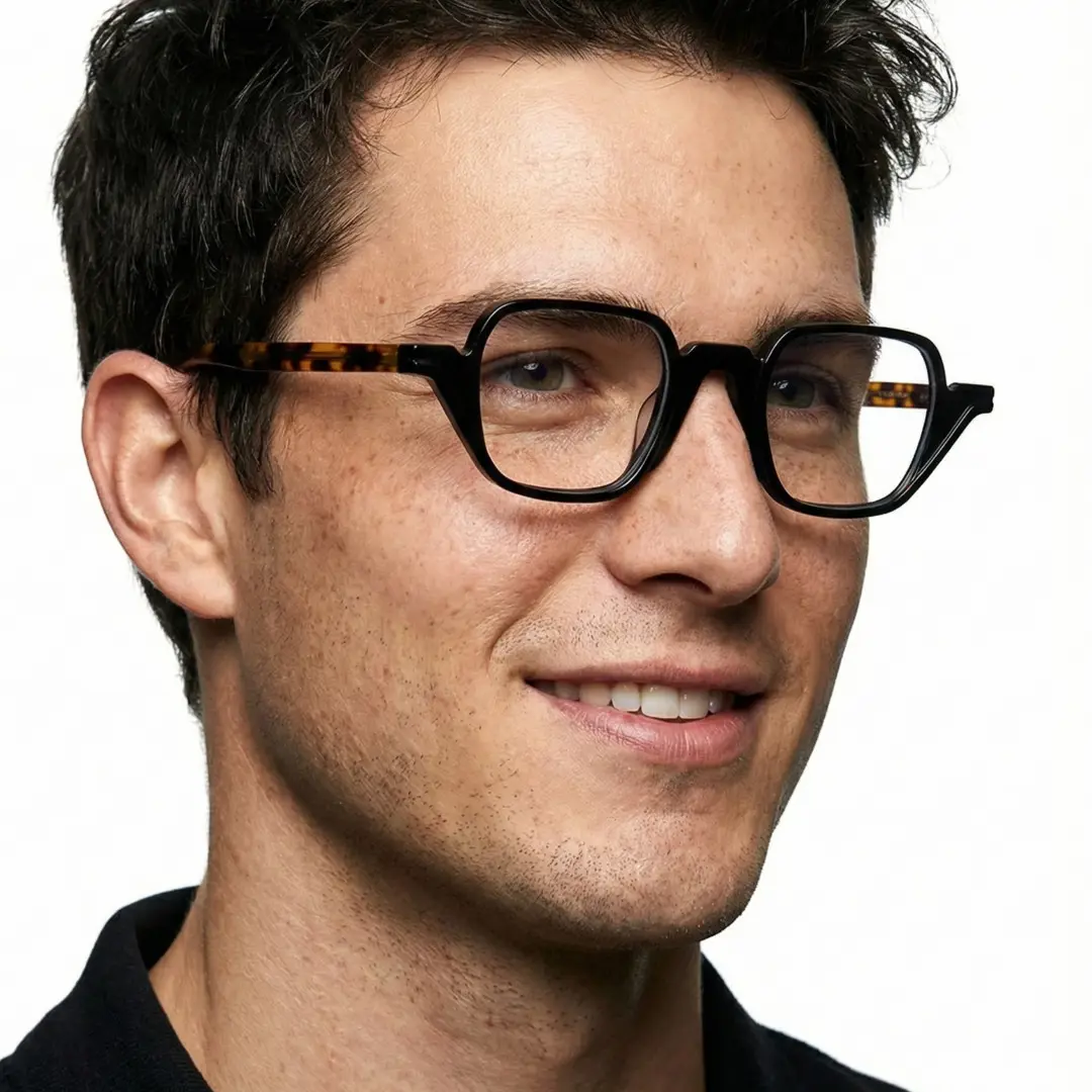 Looking away view of male wearing vintage black geometric eyeglasses, smiling, GA0242306