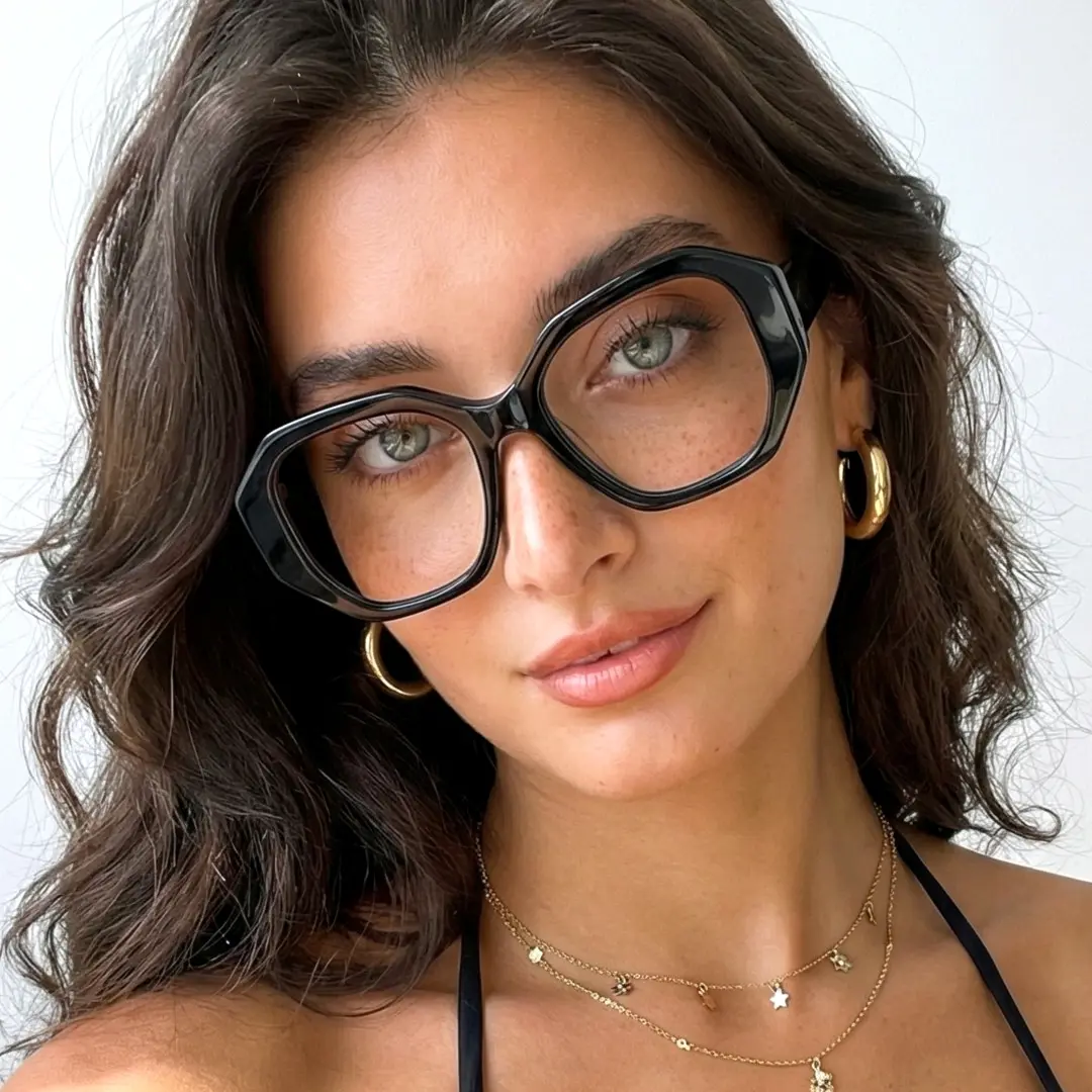 Tilted head view of female wearing black gemetric eyeglasses, smiling, GA0282509