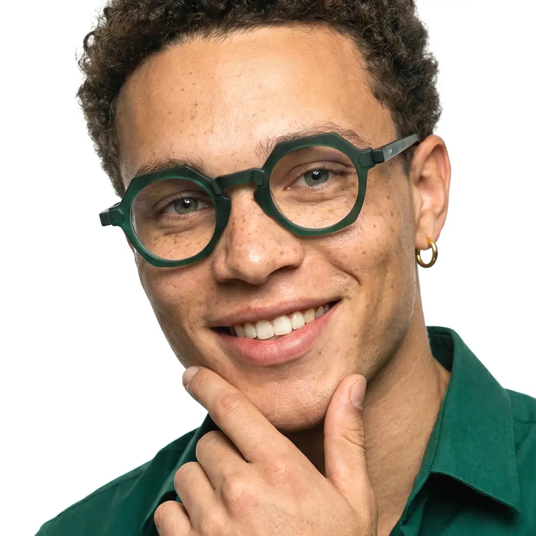 Front view of male wearing green geometric eyeglasses, hand touching face, smiling, GA0382302