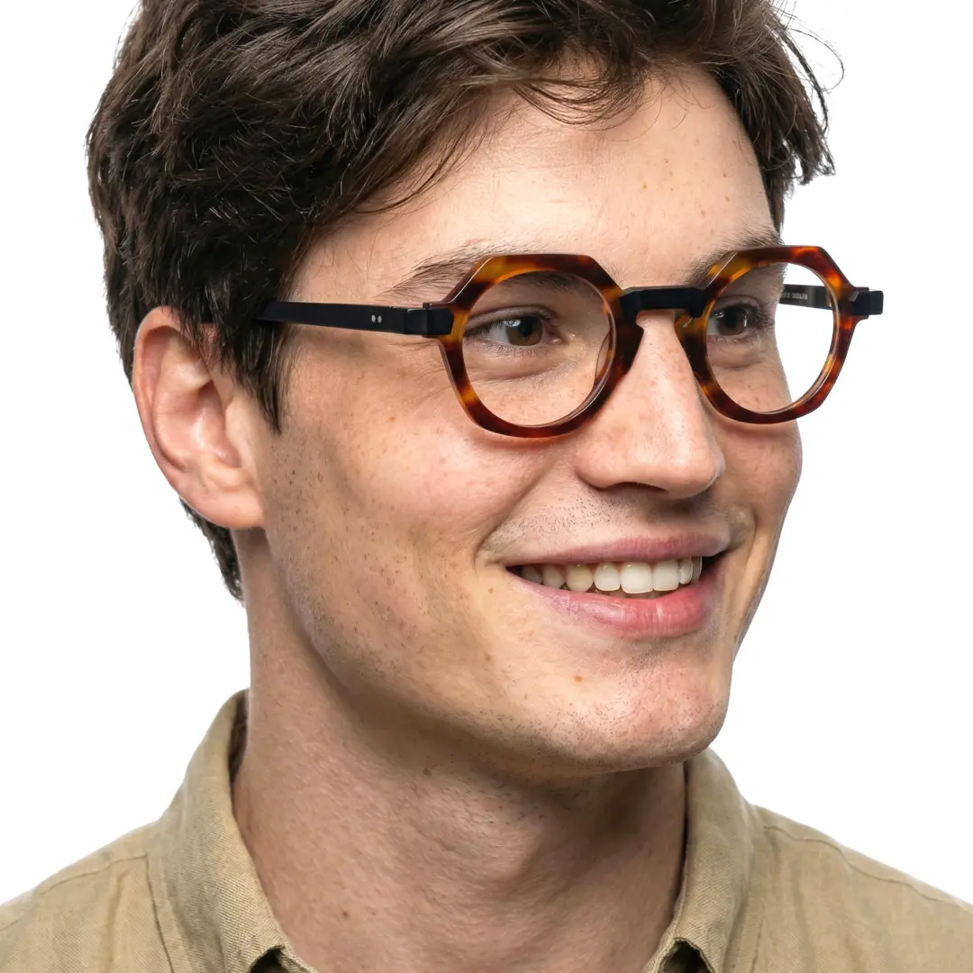 Looking away view of male wearing vintage tortoise geometric eyeglasses, smiling, GA0382302