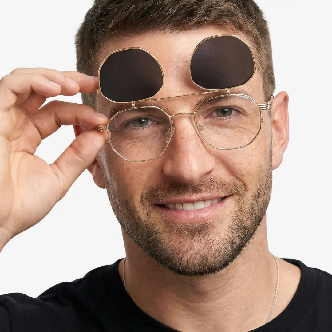 Close-up view of male wearing gold geometric flip-up eyeglasses, adjusting glasses, smiling, GM0052601