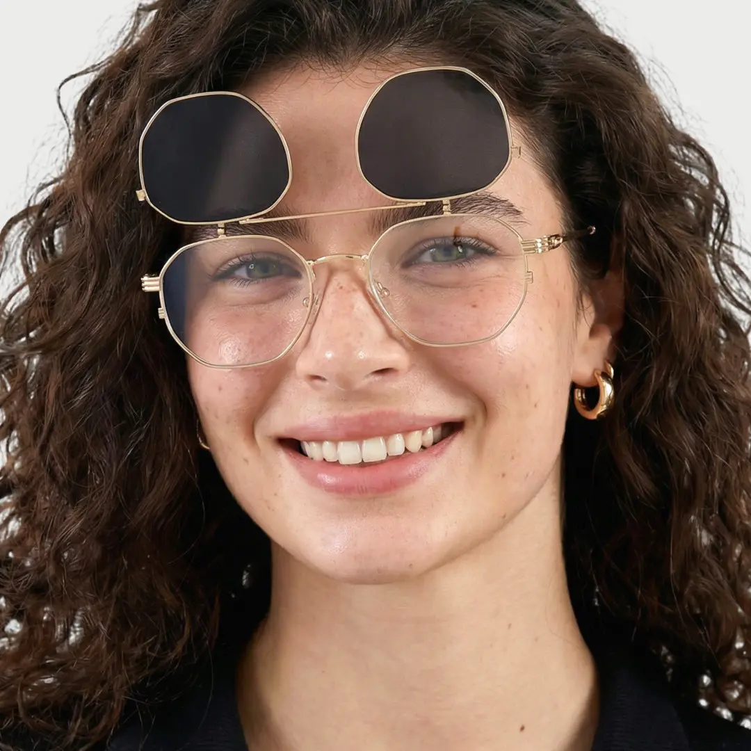 Looking straight ahead view of female wearing gold geometric flip-up eyeglasses, smiling, GM0052601