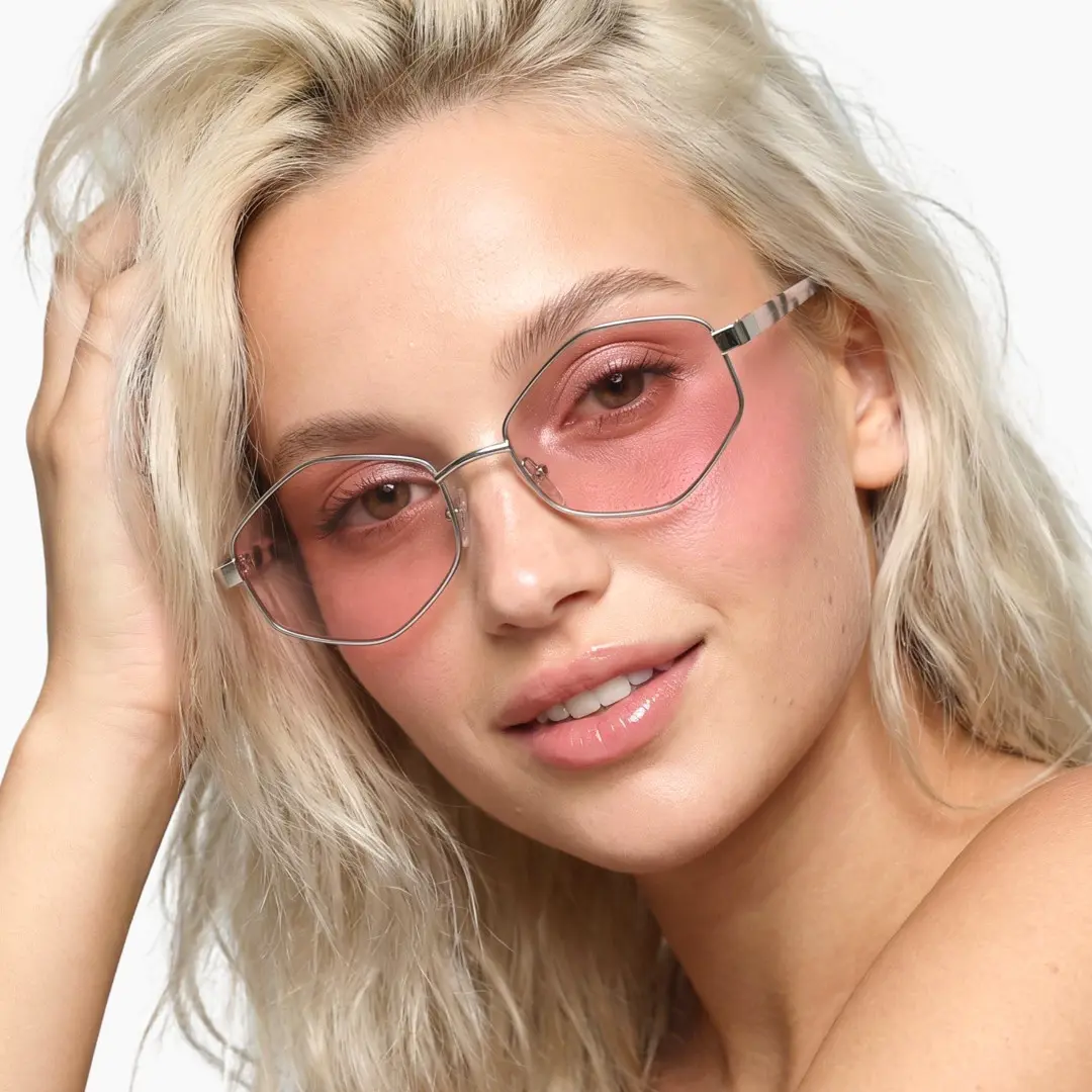 Tilted head view of female wearing fashion pink geometric sunglasses, hand in hair, natural smile, GM0062601
