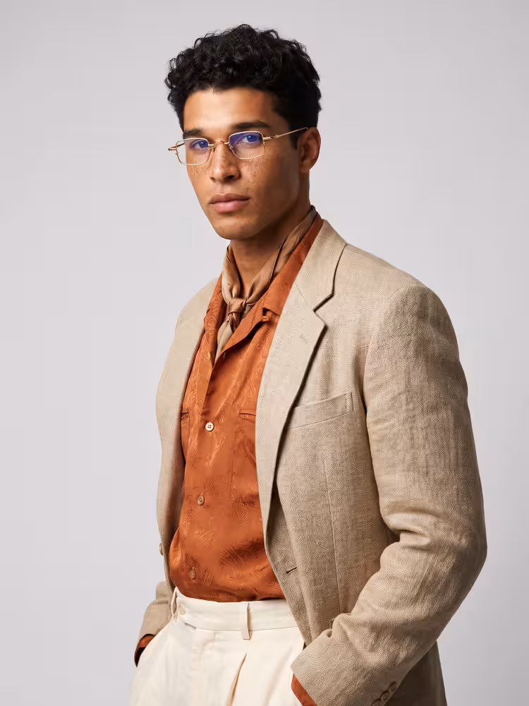 Male model wearing vintage gold geometric metal eyeglasses in an indoor minimalist portrait studio with smooth plain matte light gray wall backdrop. SPU: GM0182605