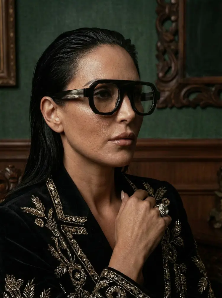Female model wearing luxury black geometric natural ox horn handcrafted eyeglasses in a classic luxury room with vintage green walls and wooden paneling. SPU: GO0242511