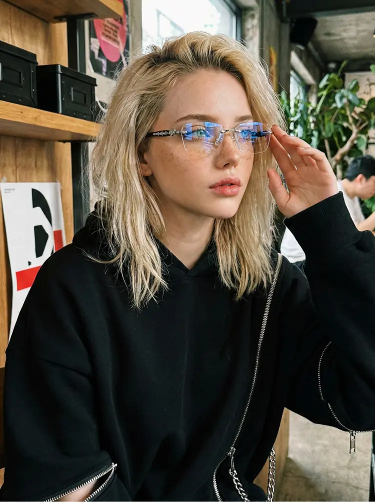 Female model wearing rimless silver geometric pc handcrafted polarized eyeglasses in an industrial cafe with wooden shelves and plants. SPU: GP0322512