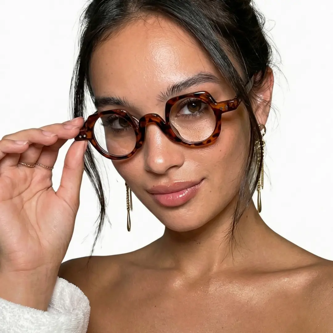 Three-quarter view of female wearing tortoise geometric eyeglasses, glasses lowered, soft smile, GP0342411