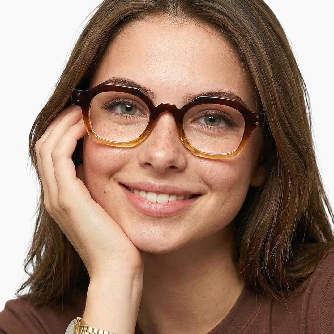 Front view of female wearing brown geometric eyeglasses, resting chin on hand, smiling, GR0092308