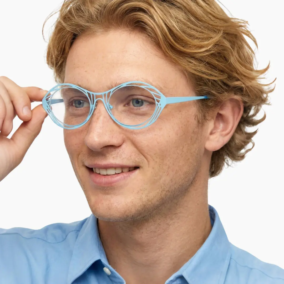 Three-quarter view of male wearing light blue oval eyeglasses, holding glasses, natural smile, OM0082212