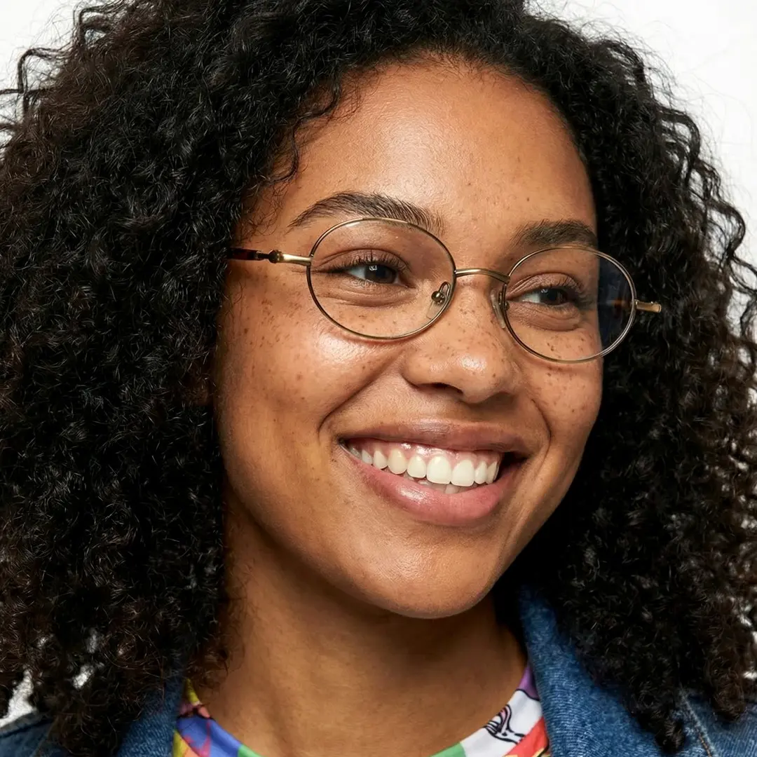 Close-up view of female wearing brown oval eyeglasses, smiling, OM0272508