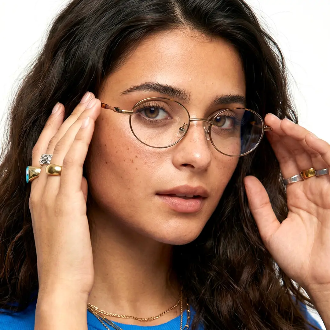 Female wearing y2k brown oval metal eyeglasses, natural expression while adjusting glasses. SPU: OM0272508