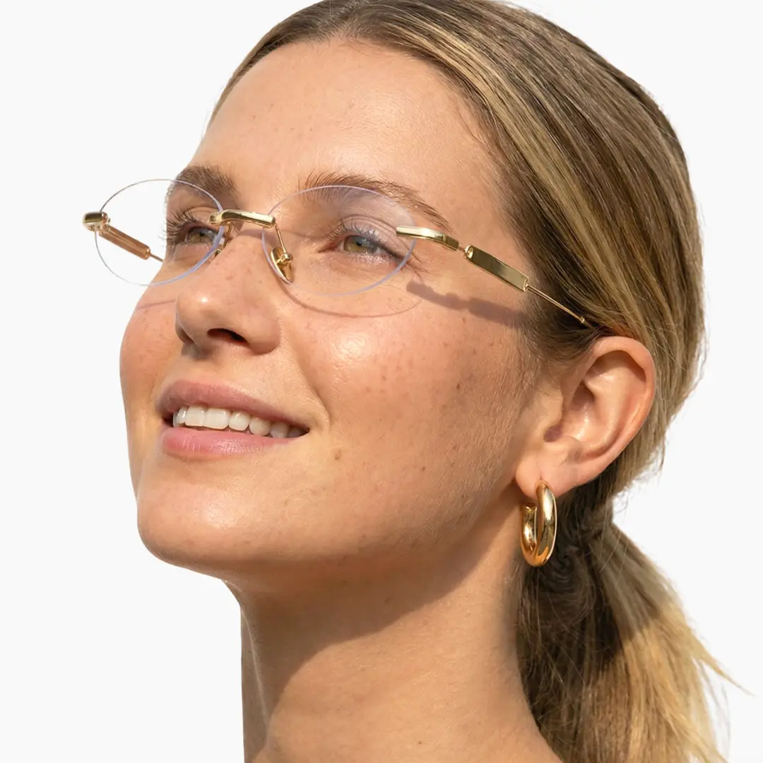 Profile view of female wearing gold oval eyeglasses, friendly smile, OM0282512
