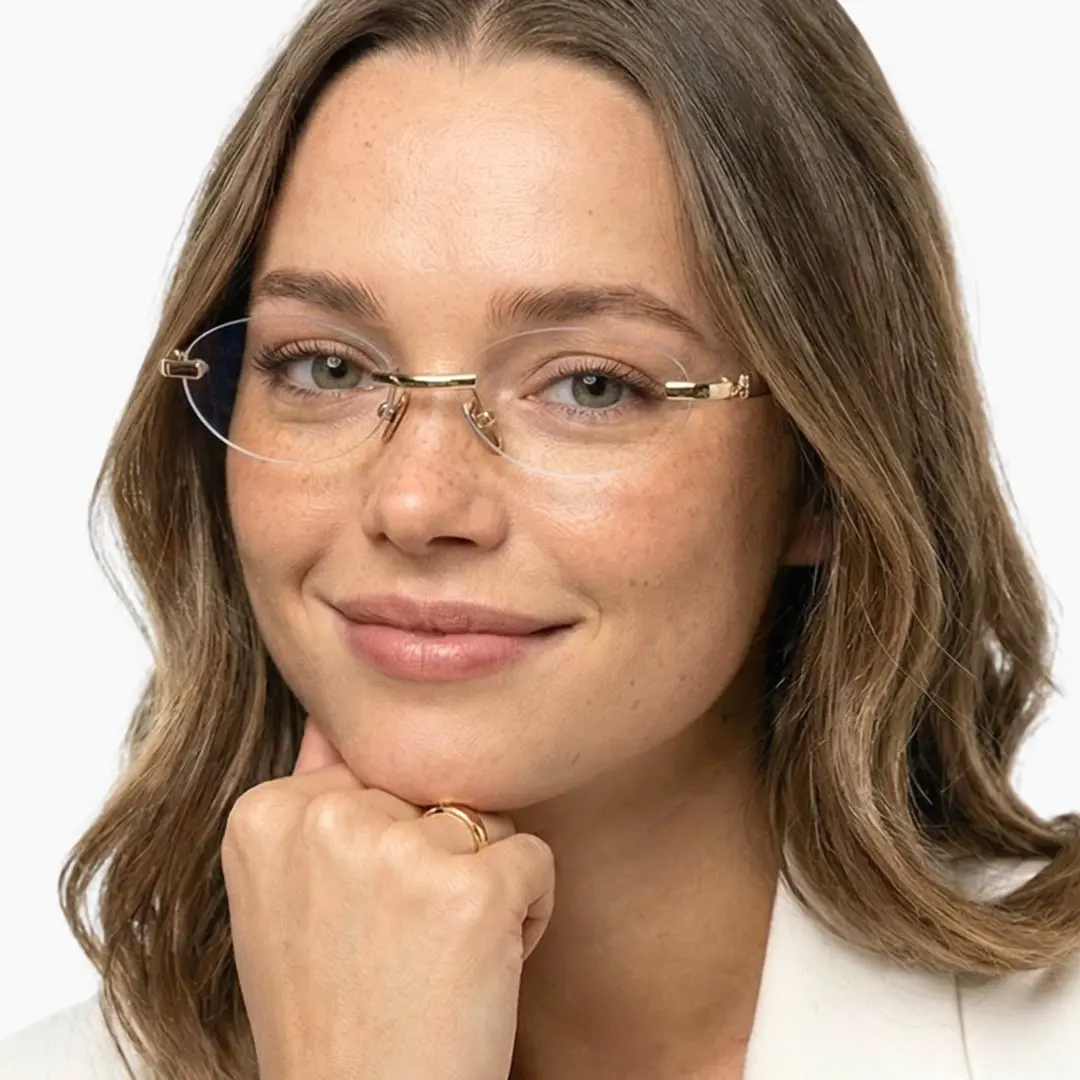 Front view of female wearing gold oval eyeglasses, resting chin on hand, natural smile, OM0282512