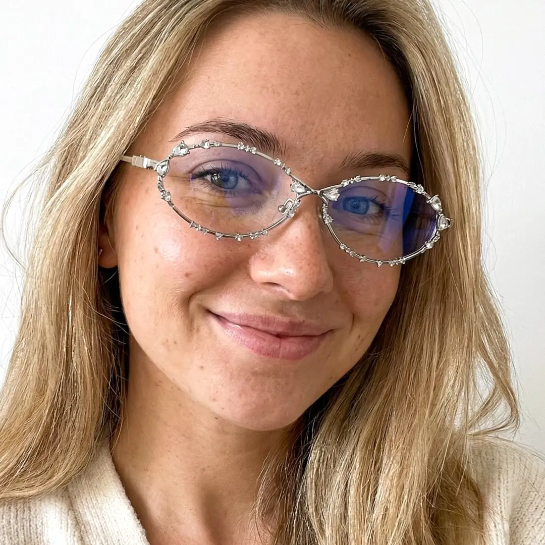 Face close-up of female wearing silver oval eyeglasses, smiling, OM0292512