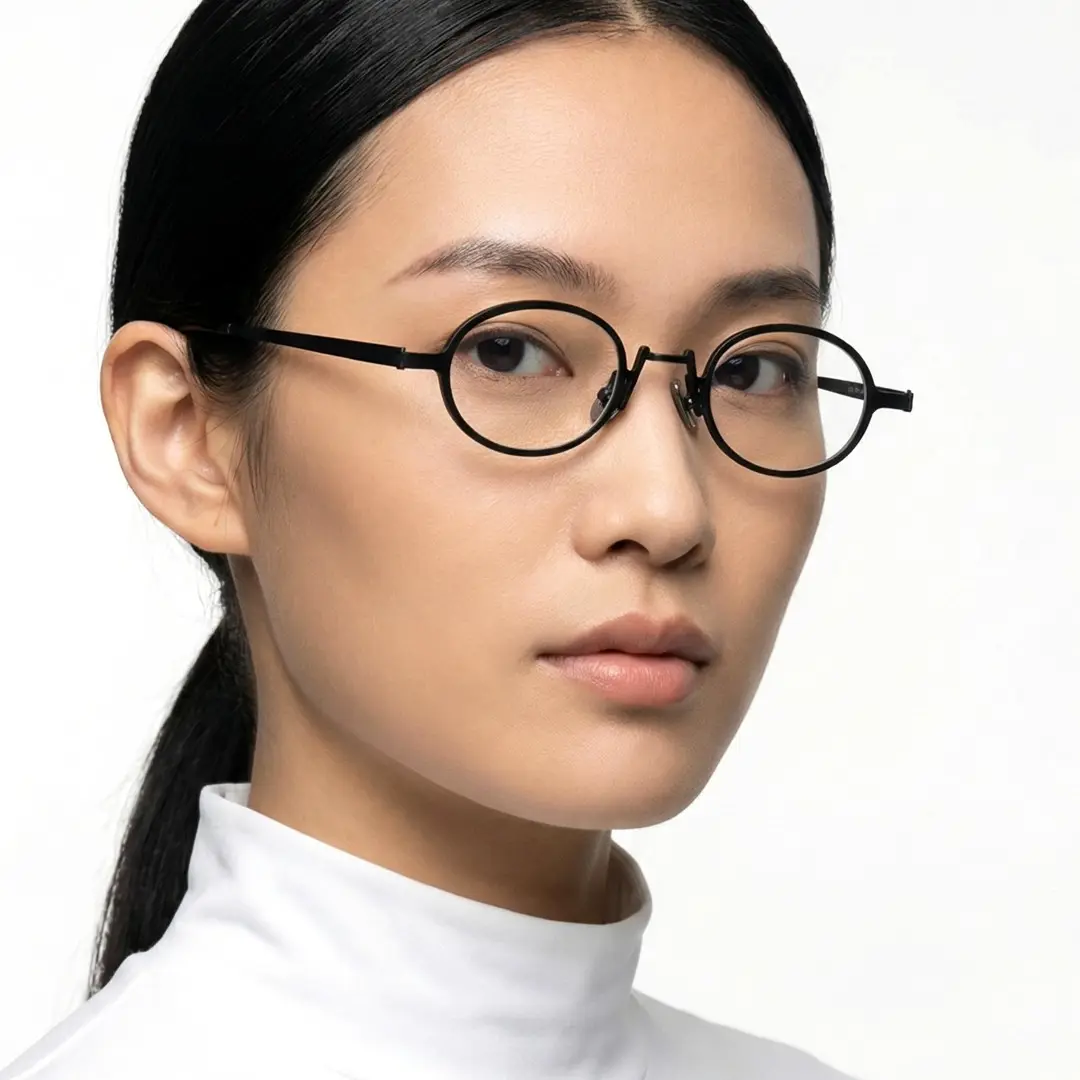 Three-quarter view of female wearing black oval eyeglasses, calm expression, OM0592302