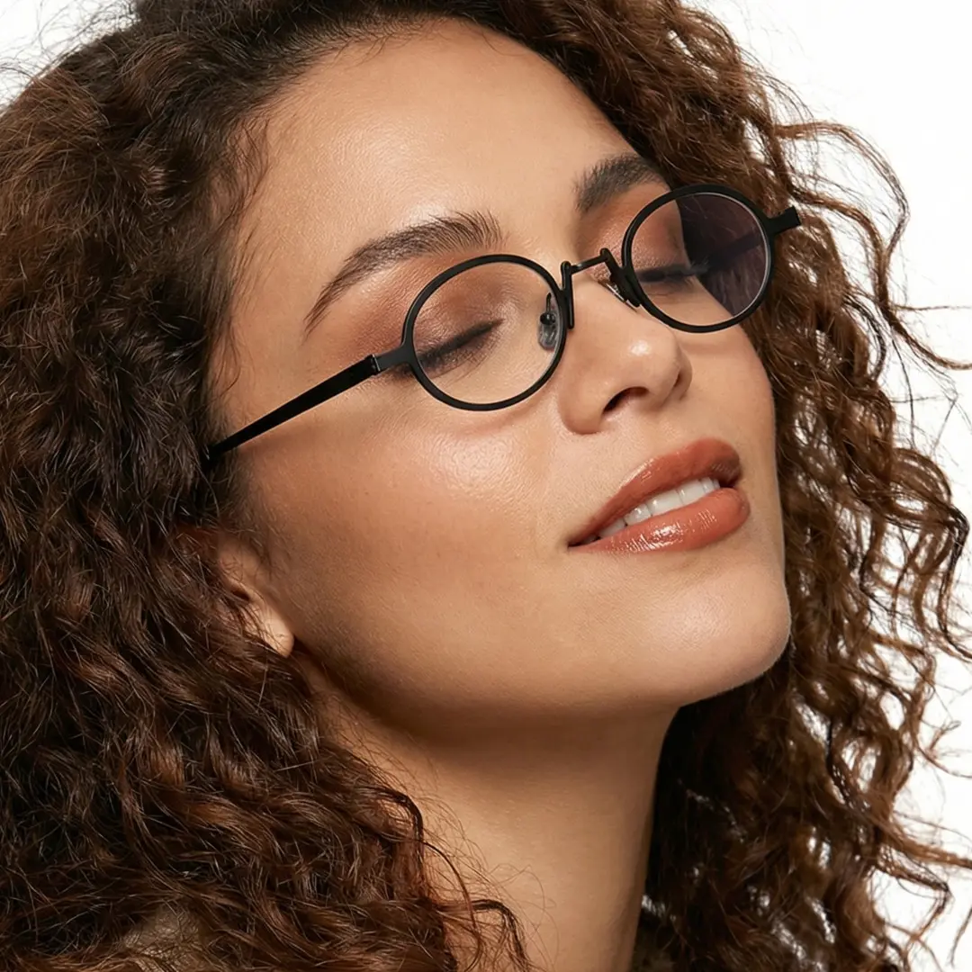 Tilted head view of female wearing black oval eyeglasses, soft smile, OM0592302