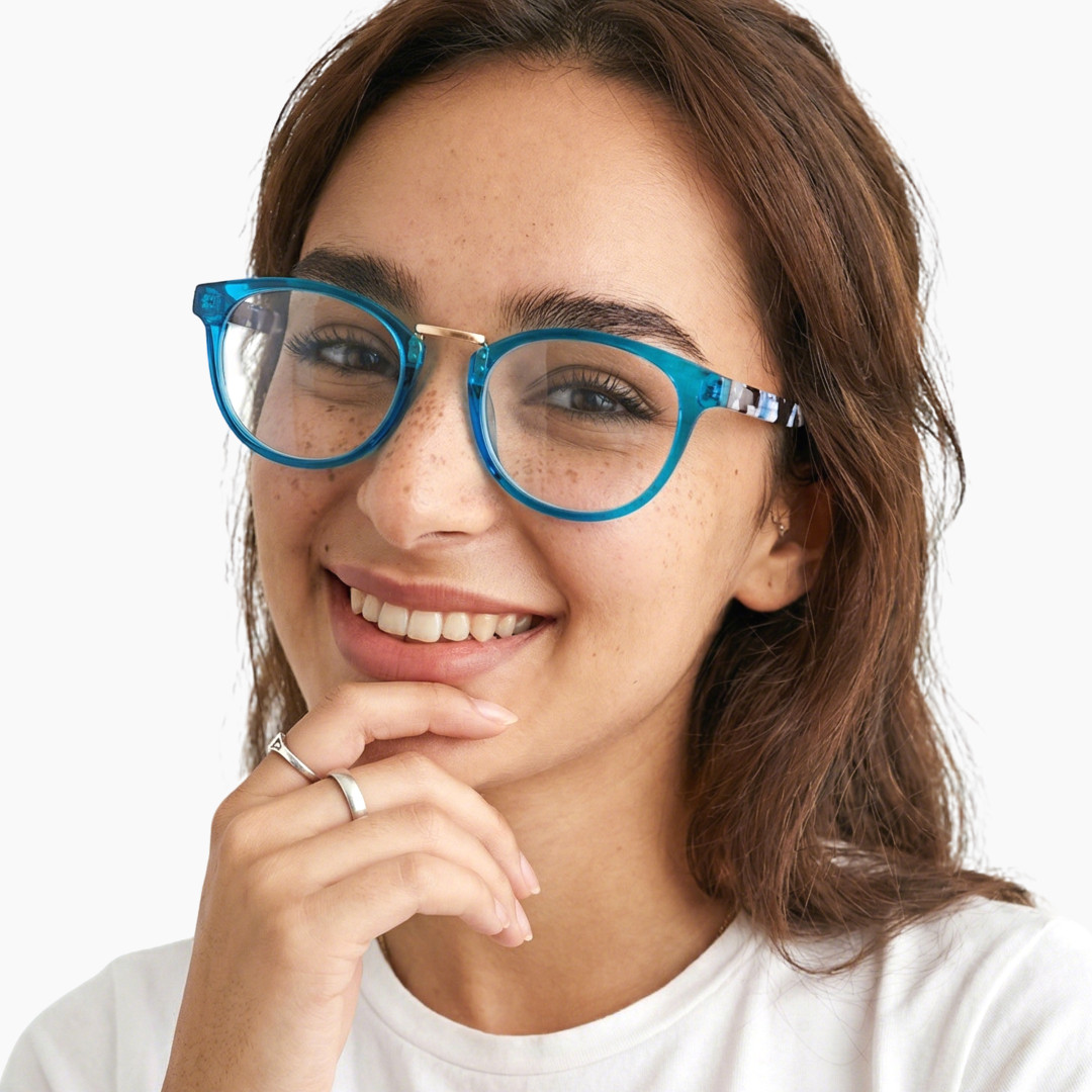 Front view of female wearing blue oval eyeglasses, finger touching lips, smiling, OP0222311