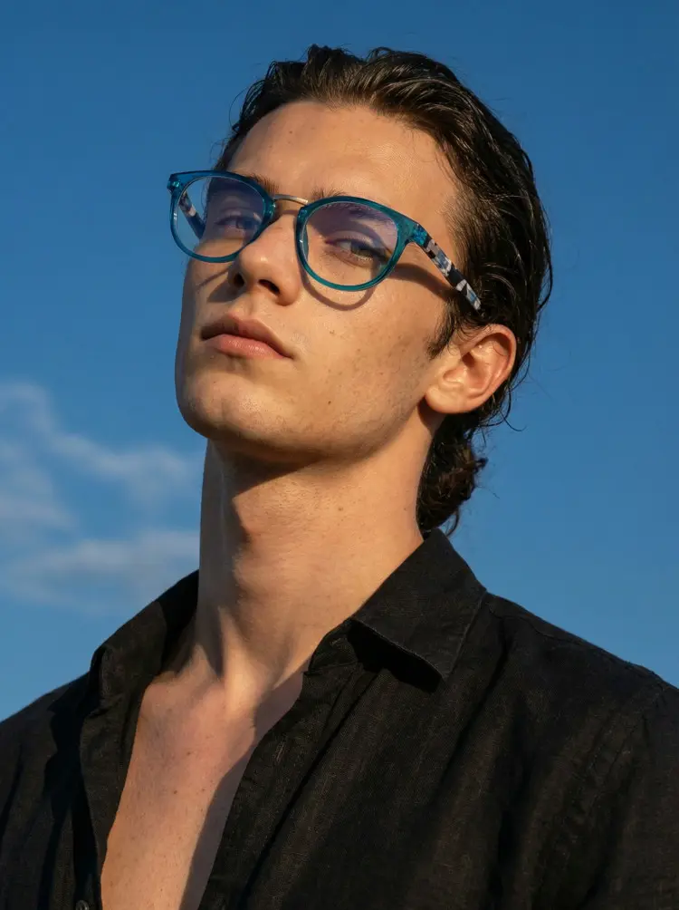 Male model wearing everyday  blue oval pc eyeglasses against a clear blue sky background. SPU: OP0222311