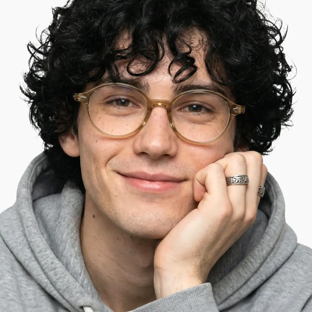 Front view of male wearing vintage bronze oval eyeglasses, resting chin on hand, natural smile, OR0082406