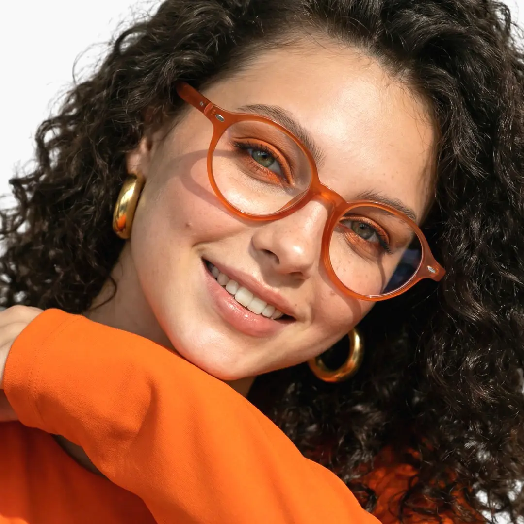 Front view of female wearing vintage orange oval eyeglasses, smiling, OR0082406