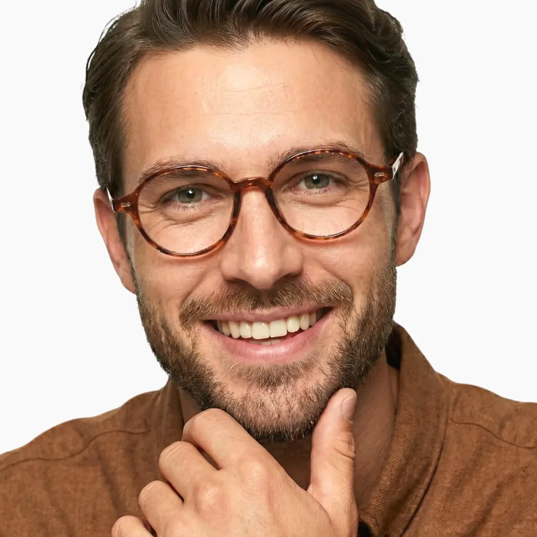 Front view of male wearing vintage tortoise oval eyeglasses, resting chin on hand, natural smile, OR0082406