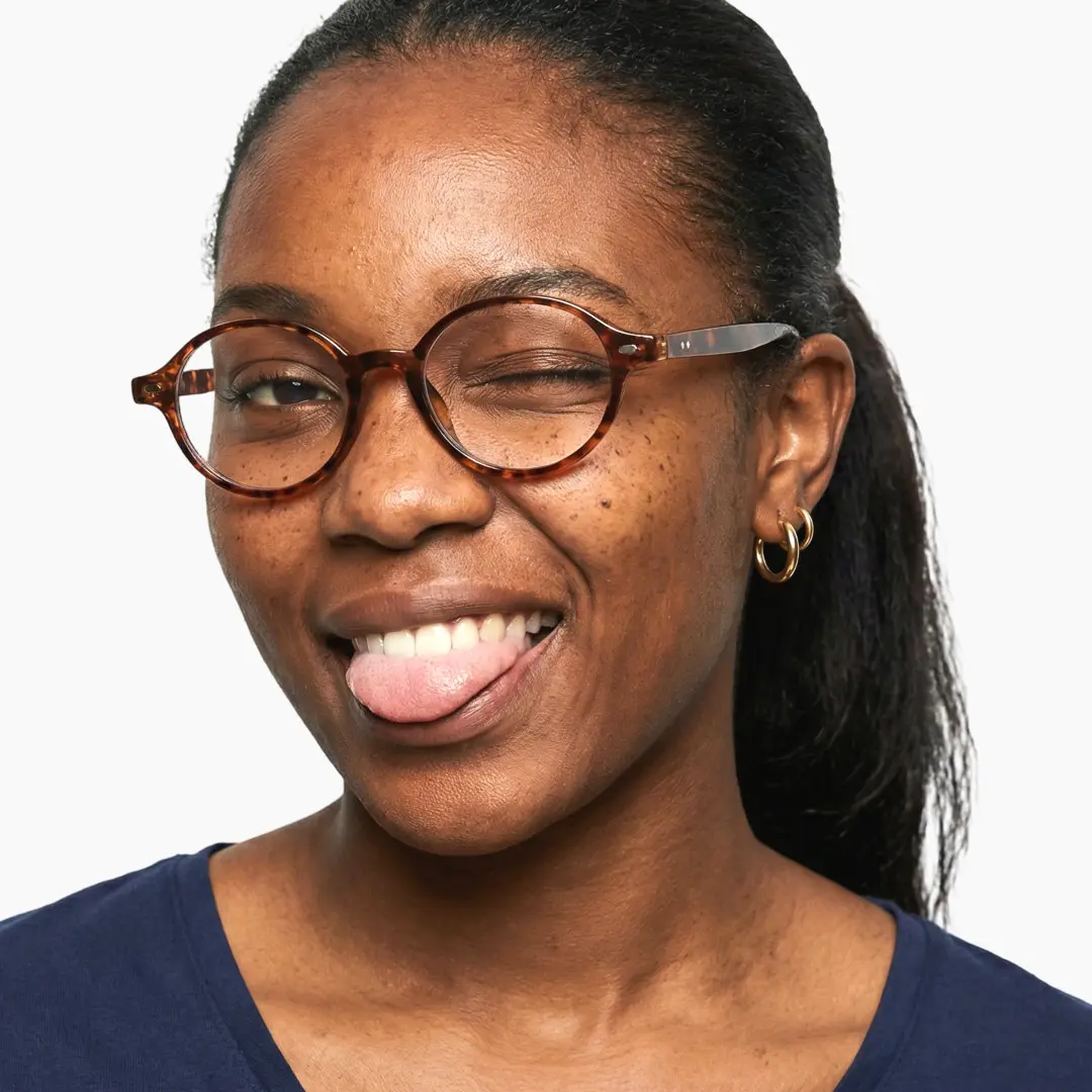 Front view of female wearing vintage tortoise oval eyeglasses, sticking out tongue, friendly smile, OR0082406