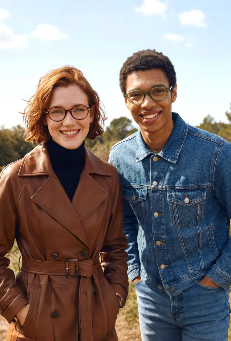Couple model wearing vintage tortoise and green oval tr90 eyeglasses in a brown leather trench coat and a denim jacket smiling together in an outdoor countryside setting. SPU: OR0082406
