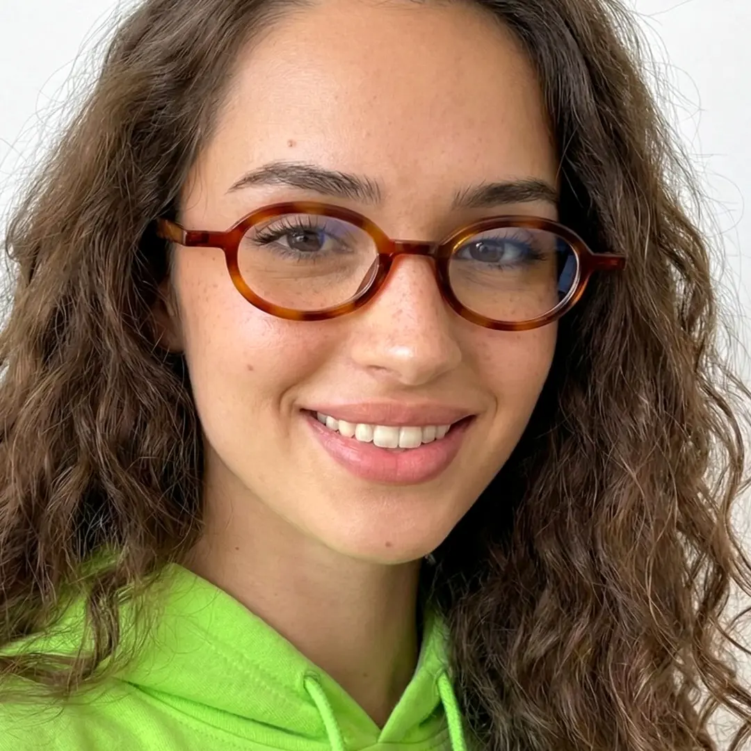 Front view of female wearing tortoise oval eyeglasses, friendly smile, OR0142510