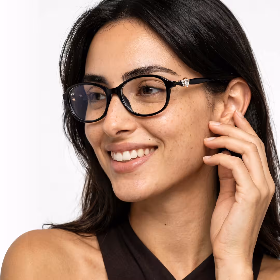 Profile view of female wearing y2k black oval eyeglasses, hand near face, smiling, OR0212411