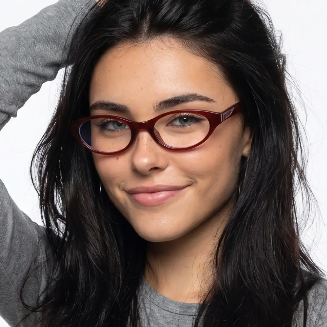Slightly angled view of female wearing y2k red oval eyeglasses, hand in hair, natural smile, OR0272512