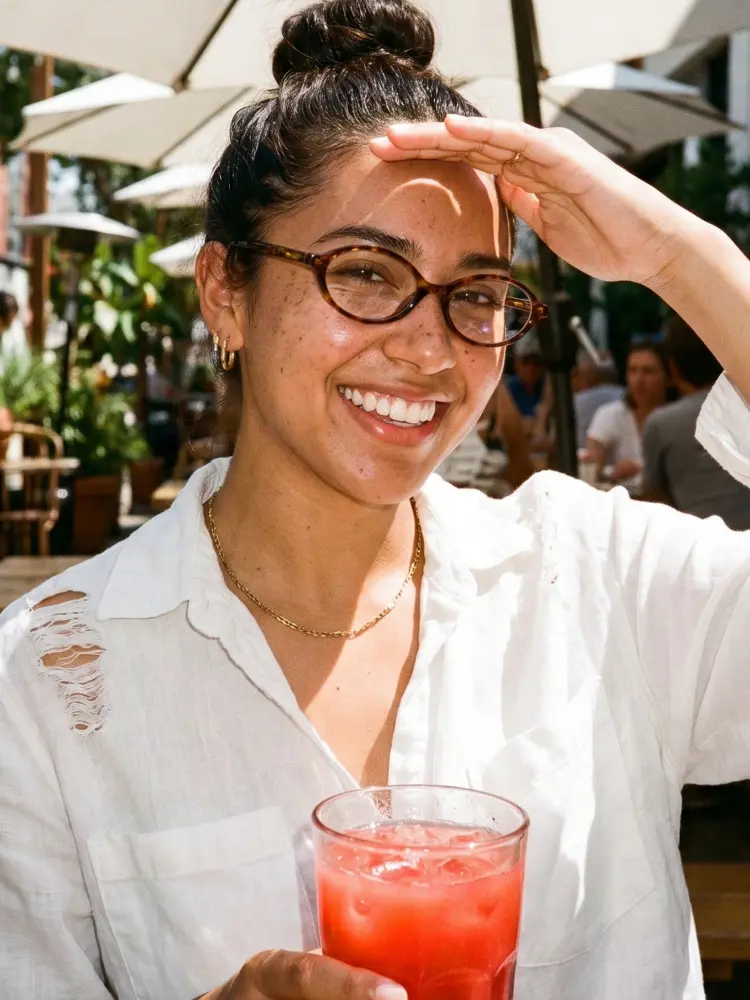 Female model wearing fashion tortoise oval tr90 eyeglasses at a sunny outdoor cafe with red drink. SPU: OR0312402