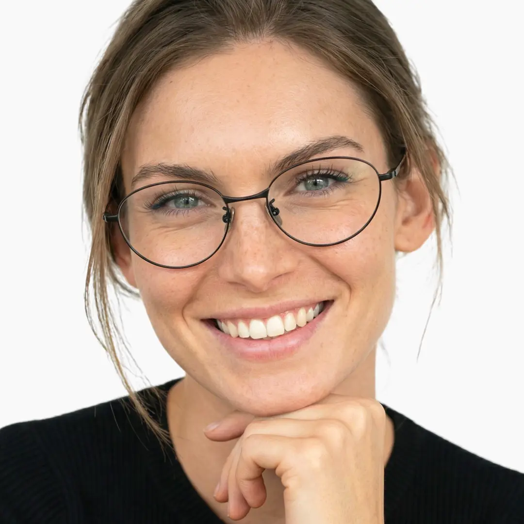 Front view of female wearing black oval eyeglasses, resting chin on hand, smiling, OT0072501