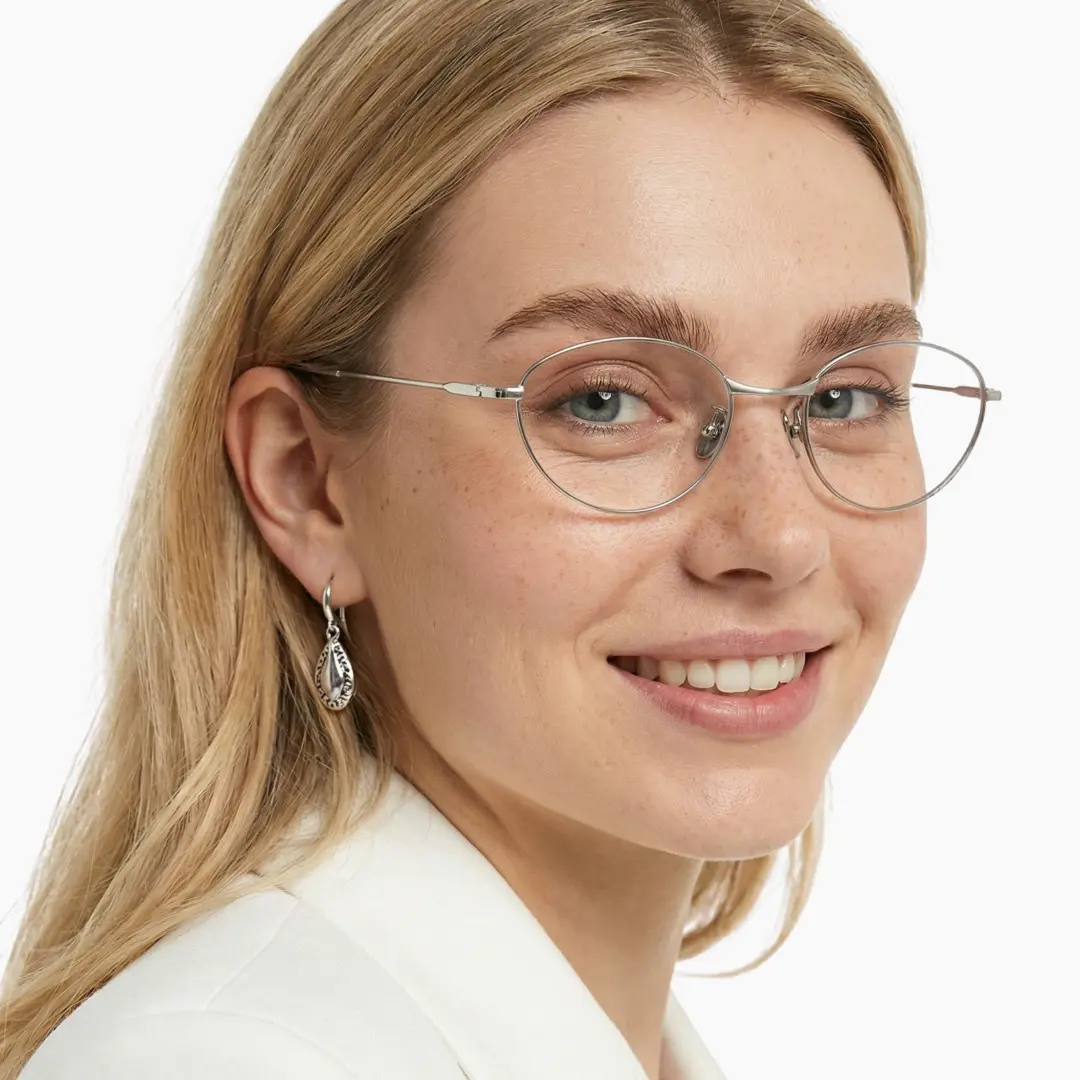 Three-quarter view of female wearing silver oval eyeglasses, smiling, OT0072501