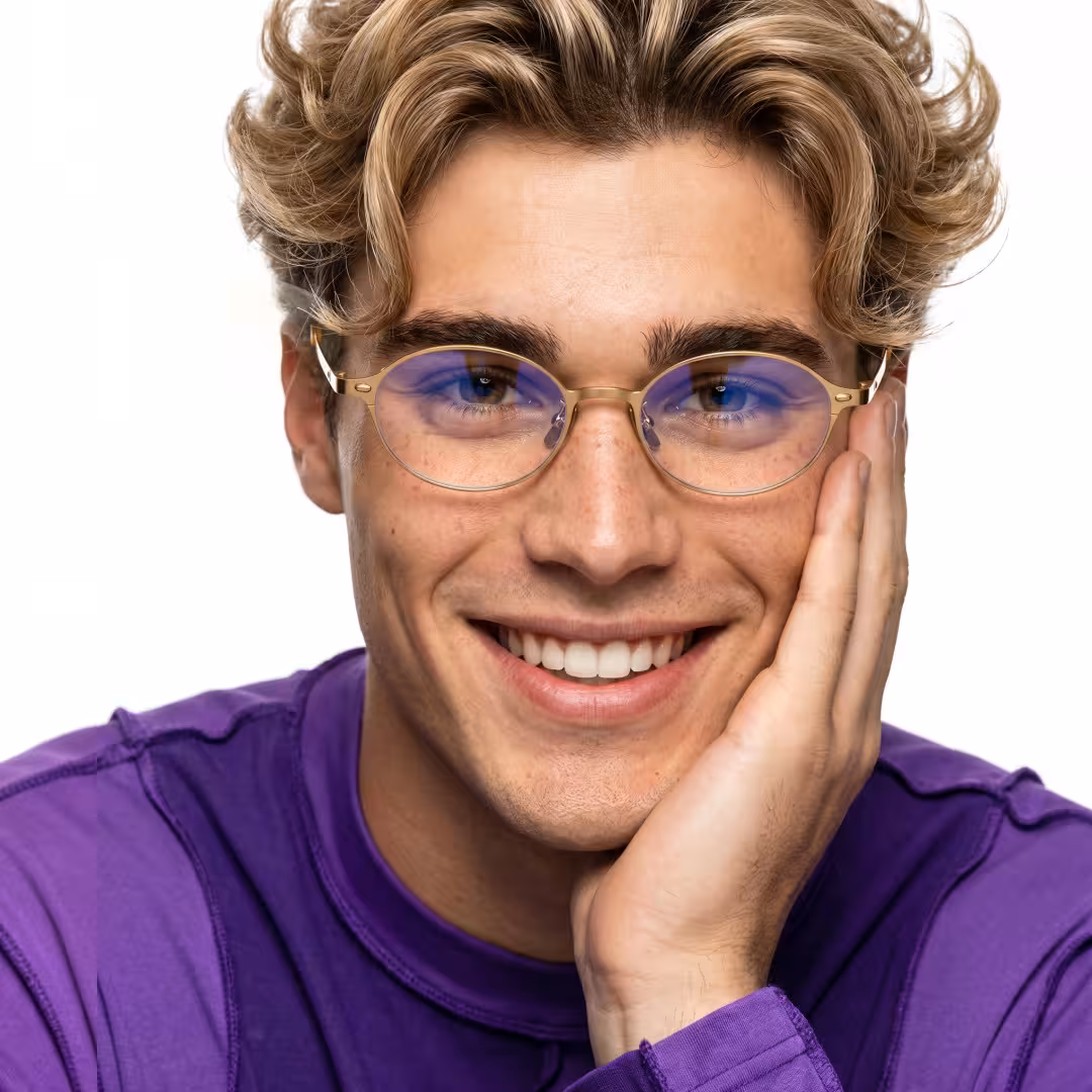Front view of male wearing y2k gold oval eyeglasses, hand near face, smiling, OT0132412
