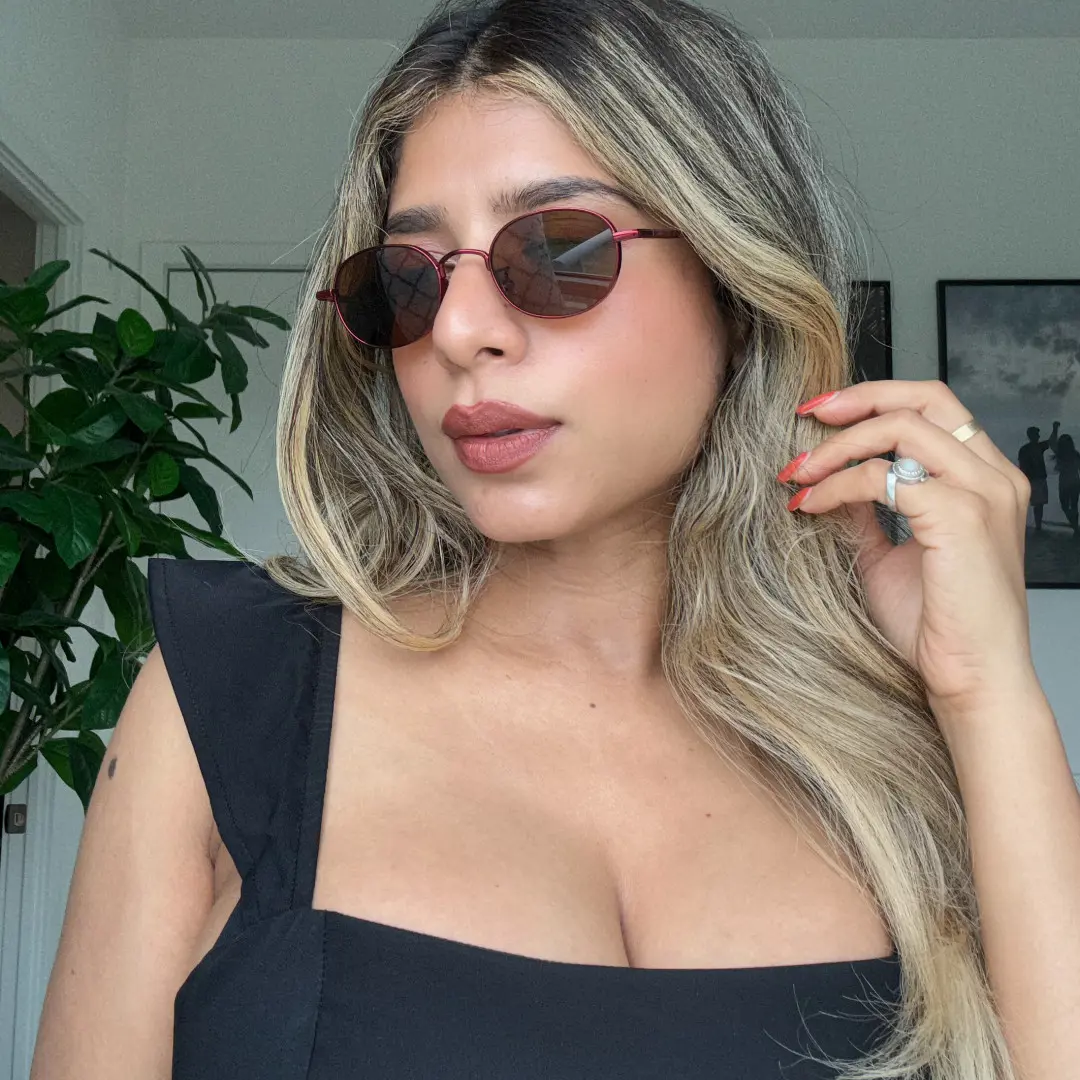 Profile view of female wearing red oval eyeglasses, hand in hair, natural expression, OT0282502