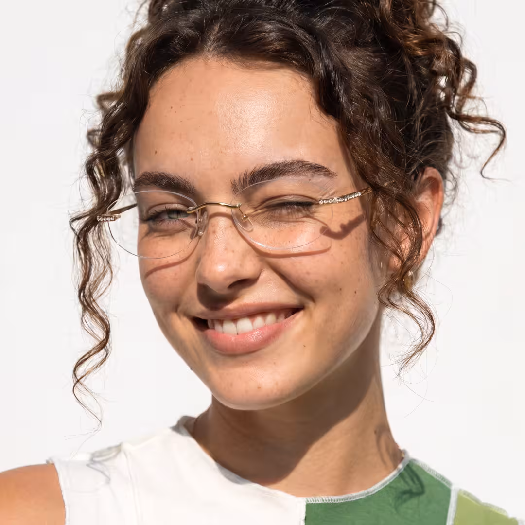 Three-quarter view of female wearing fashion gold oval eyeglasses, winking, smiling, OT0312604