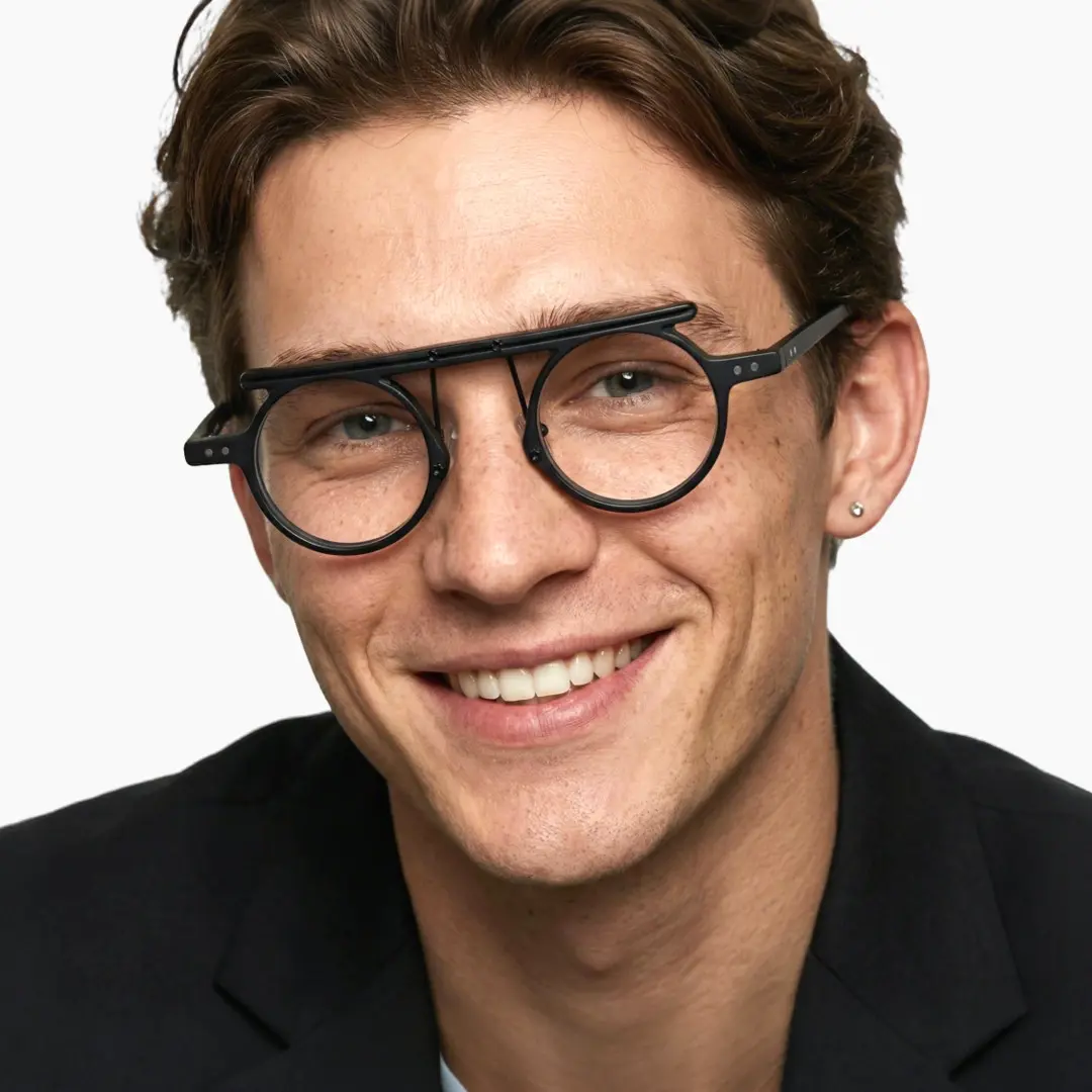 Front view of male wearing vintage black round eyeglasses, tilting head, wide smile, RA0012405