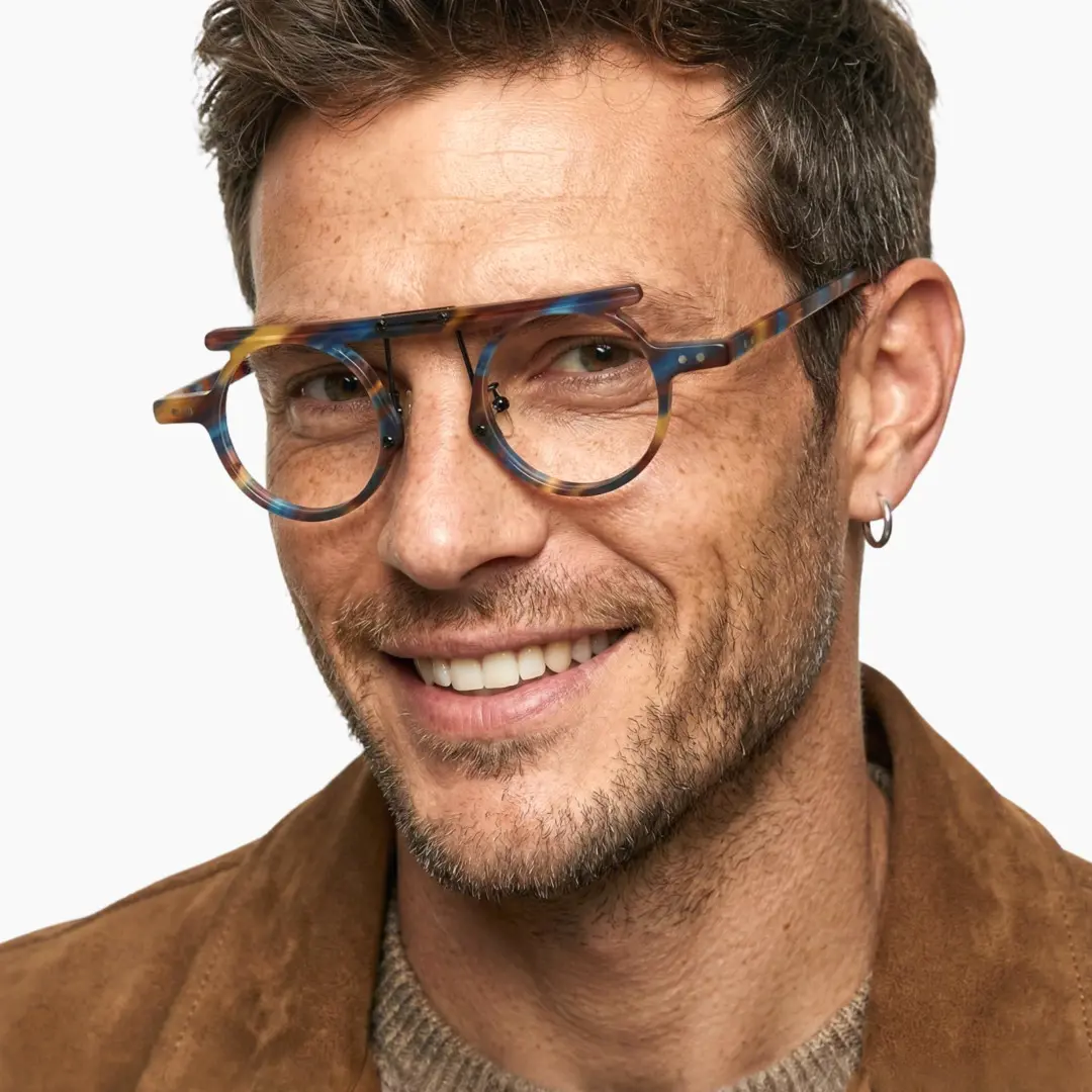 Face close-up view of male wearing vintage blue tortoise round eyeglasses, friendly smile, RA0012405