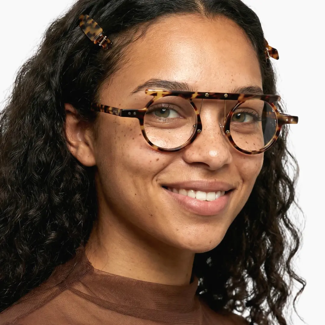Profile view of female wearing tortoise round eyeglasses, friendly smile, RA0012405