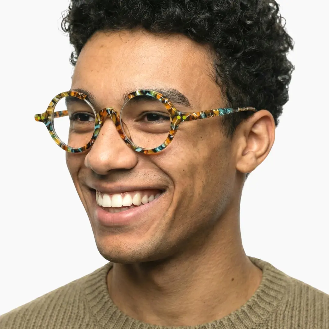 Looking away view of male wearing multicolor round eyeglasses, smiling, RA0022212