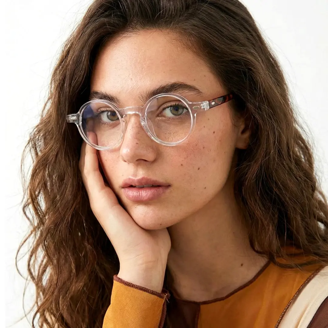 Front view of female wearing vintage clear round eyeglasses, hand near face, natural smile, RA0042301