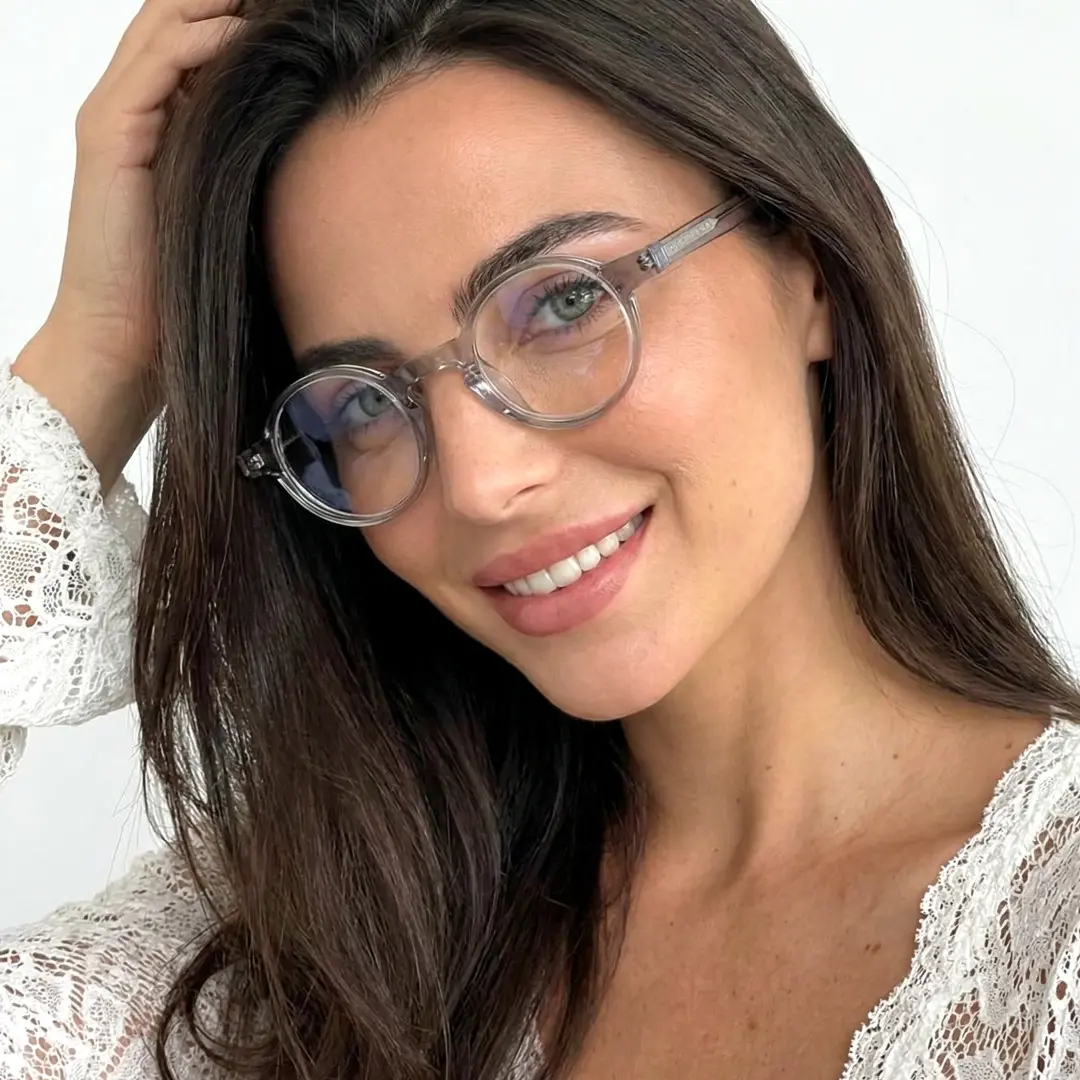 Front view of female wearing vintage silver round eyeglasses, hand in hair, smiling, RA0042303