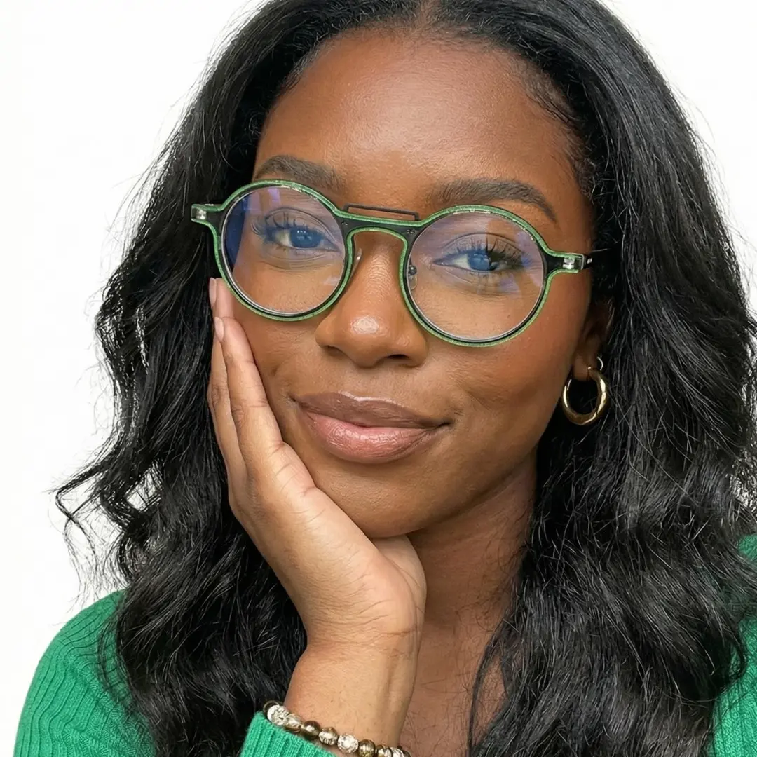 Front view of female wearing green round eyeglasses, resting chin on hand, natural smile, RA0052306