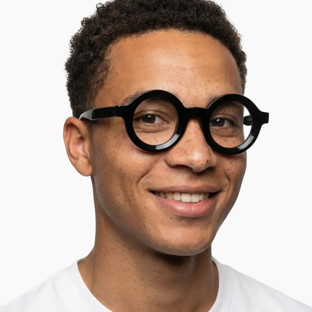 Front view of male wearing black round eyeglasses, natural smile, RA0052408