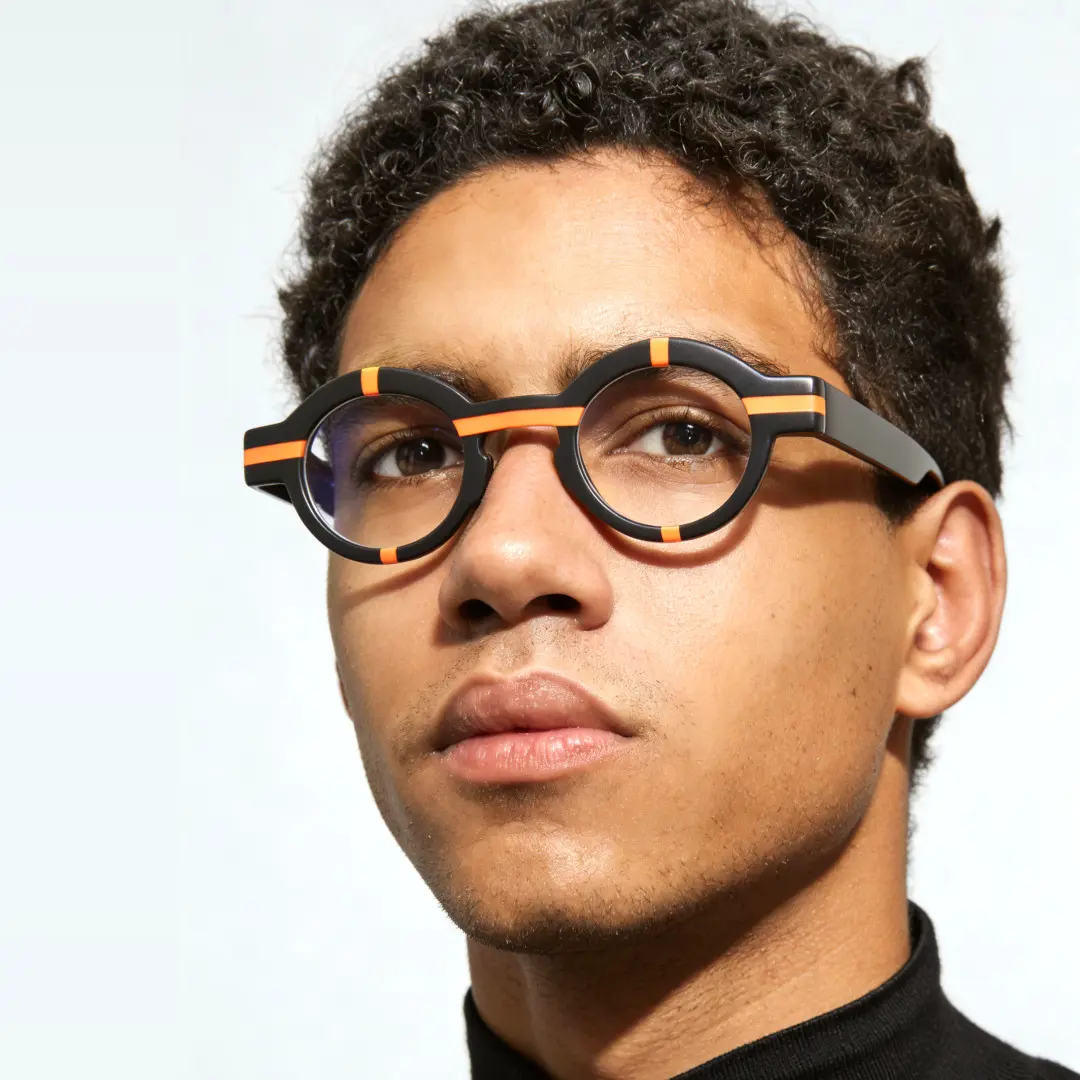 Three-quarter view of male wearing black round eyeglasses, thoughtful expression, RA0062311